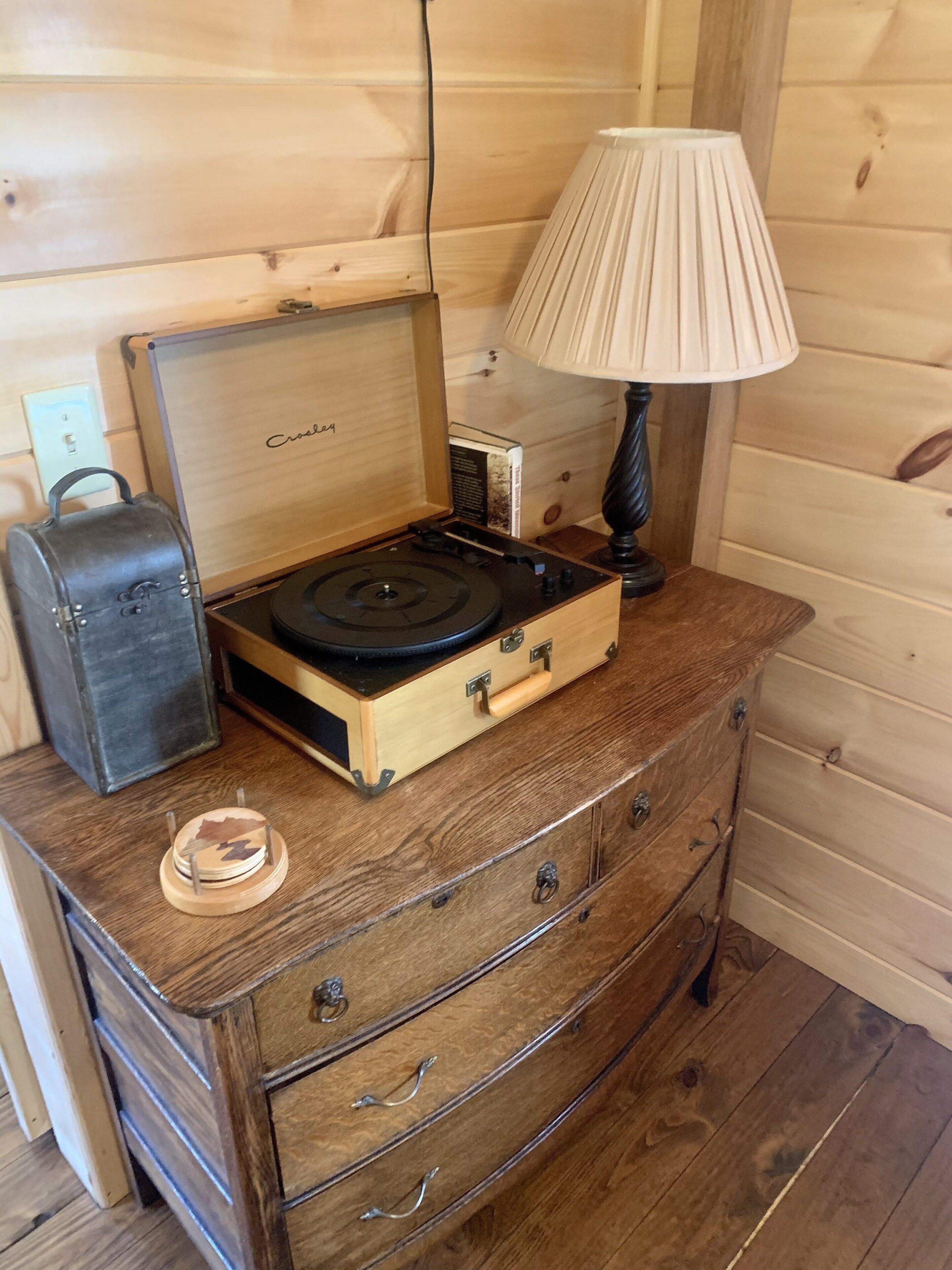 Une malle en bois contenant une platine, une lampe et une valise.