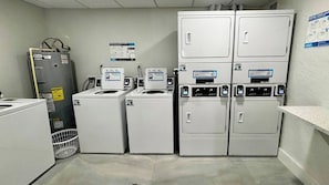 A laundry room with stacked washers and dryers, a water heater, and a wall-mounted instruction poster. - Lovers Key Beach Club Suite - Private Beach (Fort Myers Beach)