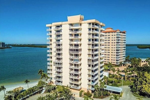 A high-rise hotel with multiple balconies, located near a body of water.
