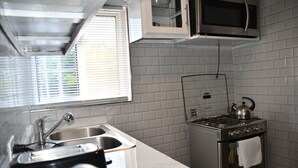 Eine kompakte Küche mit Edelstahlherd, Spüle und Mikrowelle über der Arbeitsplatte.