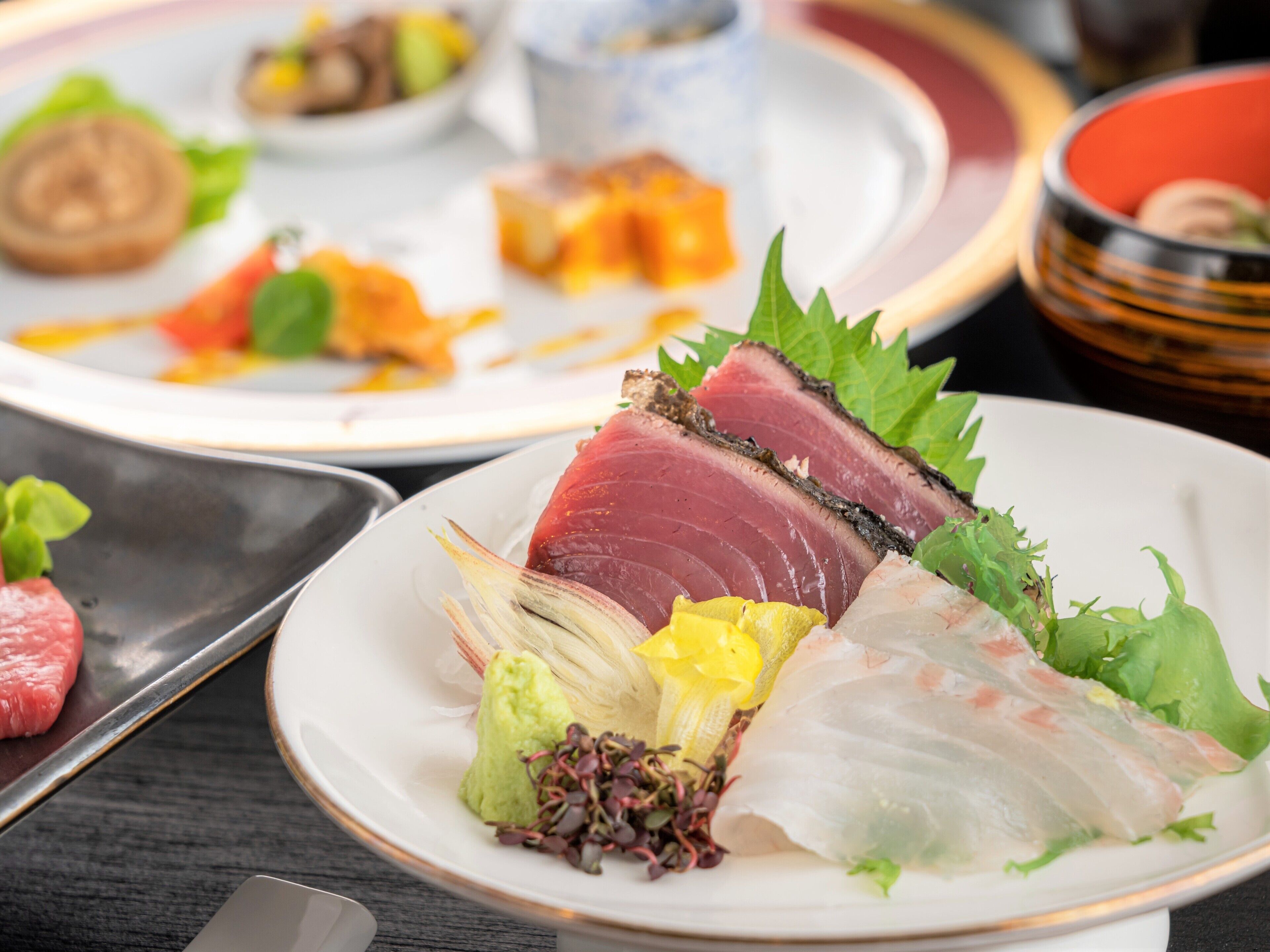 A variety of dishes on plates, including sashimi and other seafood.
