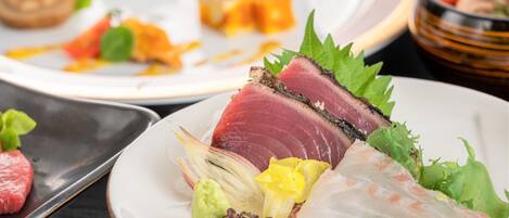 A variety of dishes on plates, including sashimi and other seafood.
