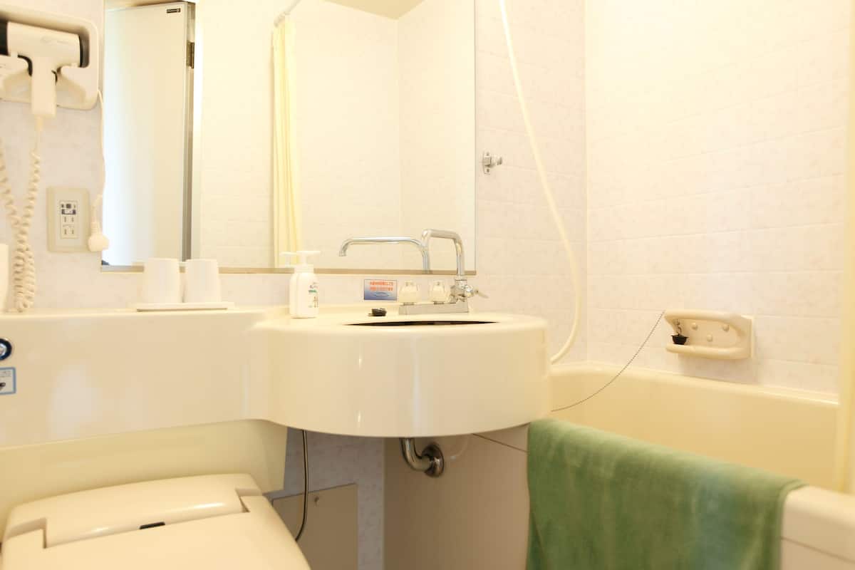 Een badkamer met toilet, wastafel, spiegel en douche.