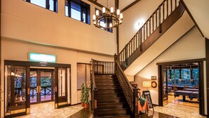 A spacious lobby with a grand staircase, a reception desk, and a view of the outdoor area. - Appi Kogen Mori no Hotel (Hachimantai)