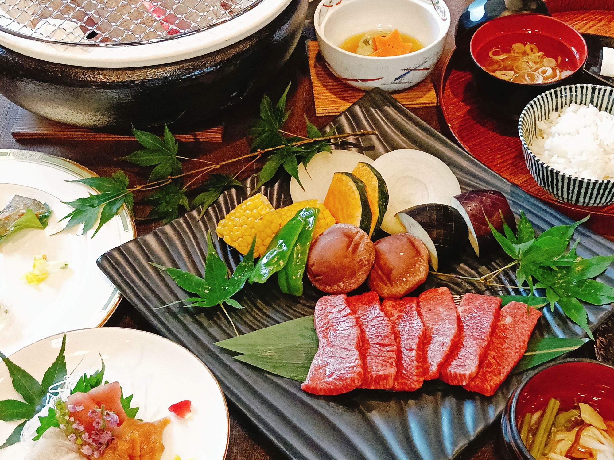 A variety of dishes including sashimi, vegetables, and rice bowls on a table.