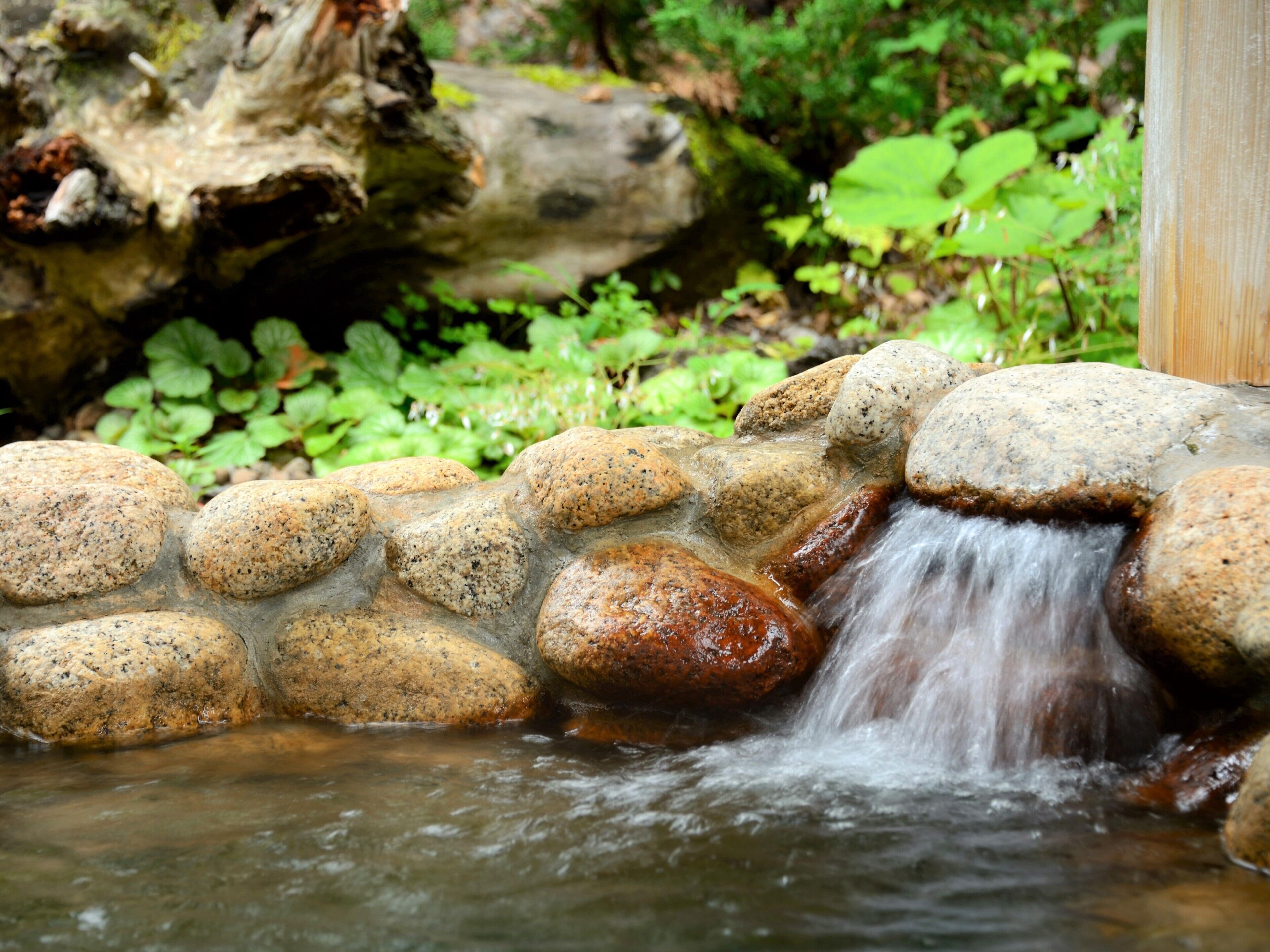 Een kleine waterval stroomt over stenen in een tuin.