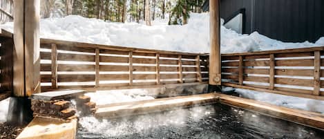 Un área de baño de aguas termales con banco y barandilla de madera.