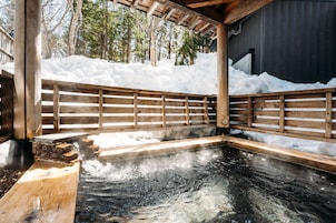 Un área de baño de aguas termales con banco y barandilla de madera.