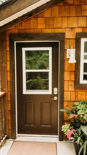 A charming entrance with a window above the door, a potted plant, and a small outdoor light.