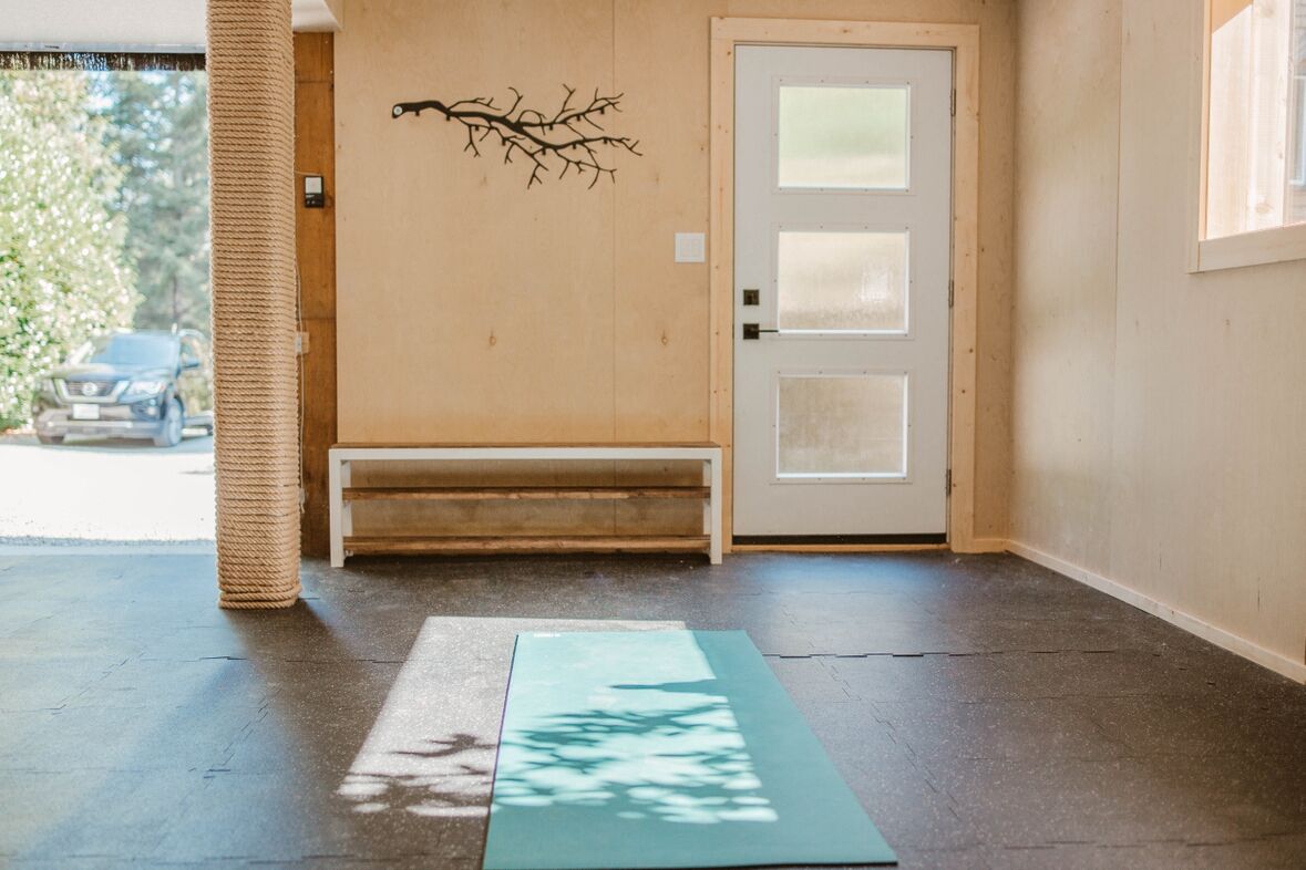 Ein Flur mit einer Bank, einer Tür und einer Yogamatte auf dem Boden.