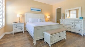 Un dormitorio con cama, mesitas de noche, un banco, cómoda y ventilador de techo.