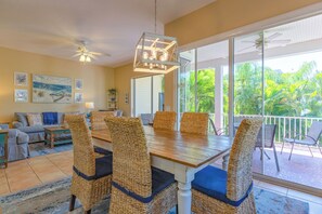 A dining area with wicker chairs, a wooden table, and a ceiling fan. - Florida Breeze: Pool home in perfect central location! (Holmes Beach)
