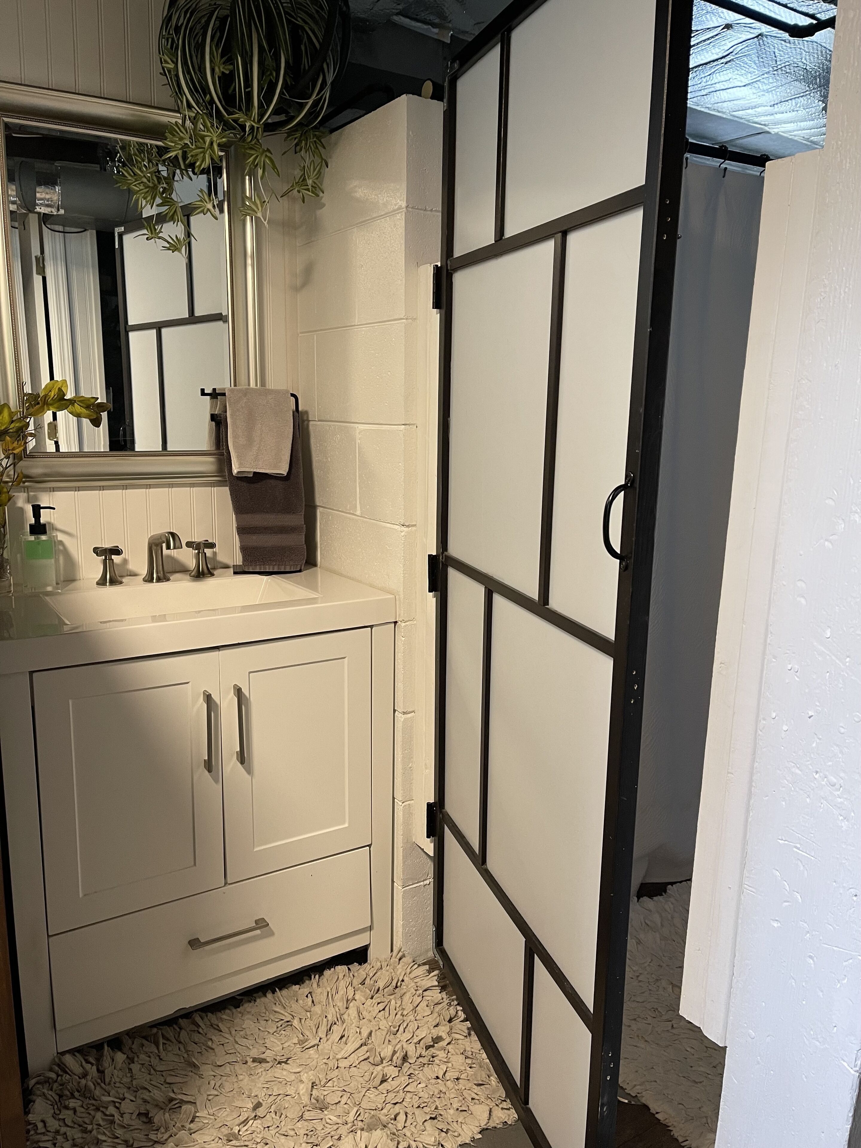 Een badkamer met een wit wastafelmeubel, een spiegel, een handdoek en een plant.