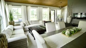 A modern living room with a sofa set, a dining table with a centerpiece, and large windows with curtains. - Cozy Home with LOTS of space- Less than 1 mile to ISU & IWU, 5 miles to airport (Normal)