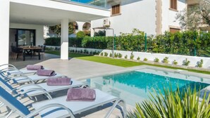 A modern building with a pool area, including lounge chairs and a dining area. - Ca na Cati by Interhome (Alcúdia)