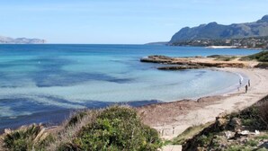 A coastal beach with clear waters, rocky outcrops, and a distant mountain range. - Ca na Cati by Interhome (Alcúdia)