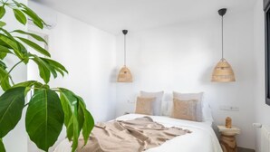 A bedroom with a large bed, two bedside tables, a hanging light fixture, and a large plant. - Ca na Cati by Interhome (Alcúdia)