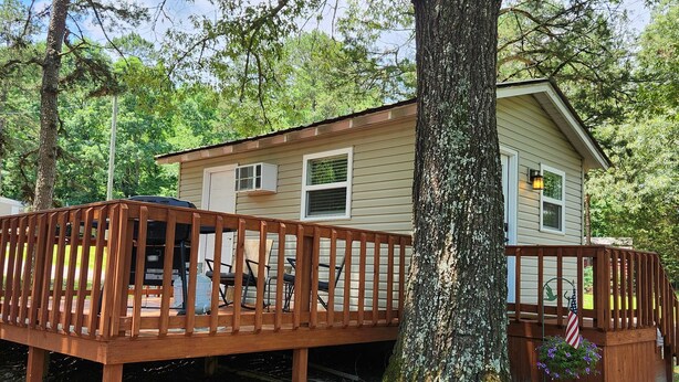 A cabin with a wooden deck, surrounded by trees. - ScrappyJax Cozy Cabin #4 (Glenwood)
