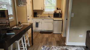 A compact kitchen with a central island, a microwave, and a coffee maker. - ScrappyJax Cozy Cabin #4 (Glenwood)