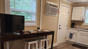 A kitchen with a dark wooden table, white cabinets, a window with blinds, and a large rug on the floor. - ScrappyJax Cozy Cabin #4 (Glenwood)
