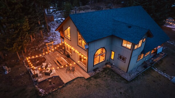 Una casa de dos pisos con un balcón, ventanas amplias e iluminación exterior.