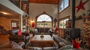 Un salón amplio con sofás de cuero, una mesa de centro de madera, chimenea y un gran ventanal de arco.