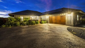 Una casa moderna con garaje, entrada para vehículos y jardines bien cuidados.