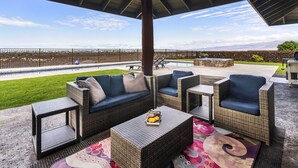 Un patio al aire libre con mobiliario de mimbre, una piscina y vistas al paisaje.