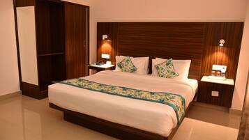 Habitación de hotel con una cama grande, cabecero de madera, dos mesitas de noche con lámparas y un armario.