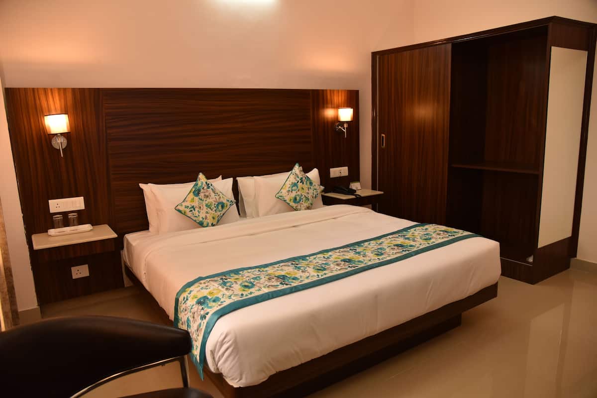 Een hotelkamer met een groot bed, twee nachtkastjes, een garderobe en een stoel.