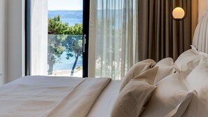 Une chambre avec un grand lit, une vue sur la mer et une fenêtre avec des rideaux.