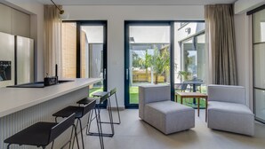 Une cuisine moderne avec un coin bar, de grandes fenêtres et une vue sur le jardin.