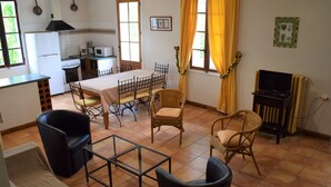 A spacious living area with a dining table, chairs, a sofa, and a television. - Le Hameau Montplaisir, its 4 houses, 36 beds and 2 large swimming pools! (Béziers)