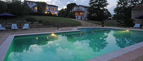 A swimming pool with lounge chairs and a landscaped area with houses in the background.
