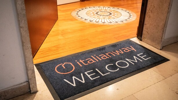 A hotel entrance with a doormat that reads "Italianway WELCOME" and a circular mosaic design on the floor. - Italianway - Gradisca 8 (Udine)