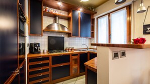 A modern kitchen with wooden cabinets, a stainless steel range hood, and a built-in oven. - Italianway - Gradisca 8 (Udine)