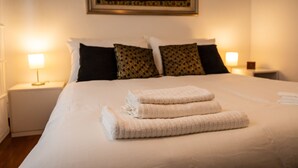 A neatly made bed with folded towels, a framed picture on the wall, and two bedside lamps. - Italianway - Gradisca 8 (Udine)
