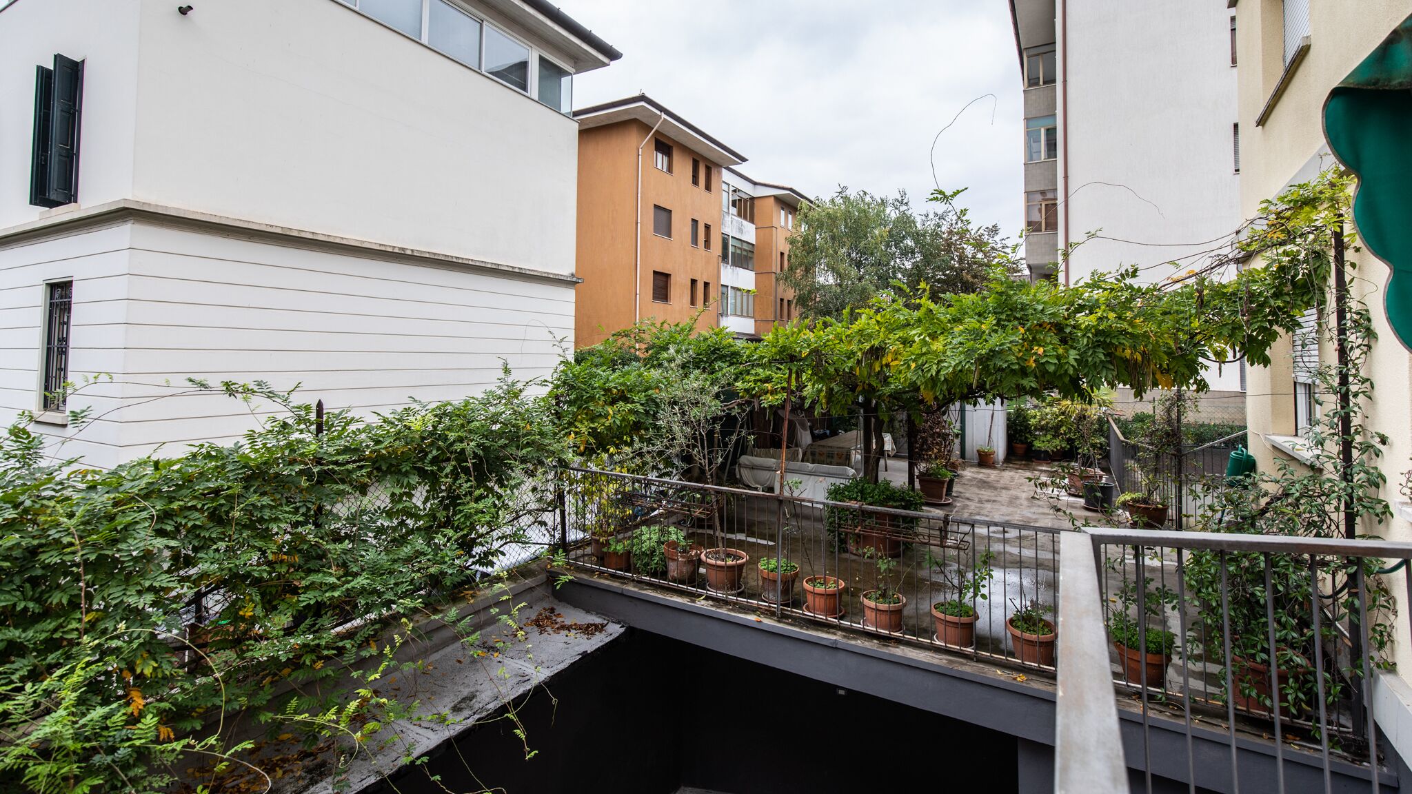 A narrow alleyway with a small bridge, surrounded by buildings with balconies and potted plants.