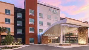 A multi-story hotel with a modern facade, a covered entrance, and a landscaped front area.