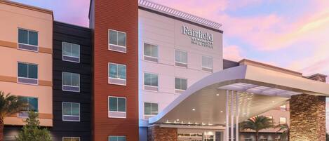 A multi-story hotel with a modern facade, a covered entrance, and a landscaped front area.