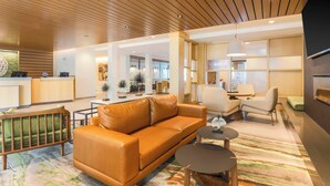 A modern hotel lobby with a leather sofa, a reception desk, and a seating area with a patterned rug.
