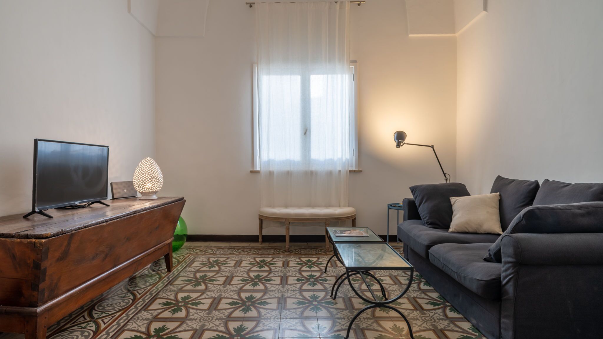 A living room with a TV, a lamp, a sofa, and a table.