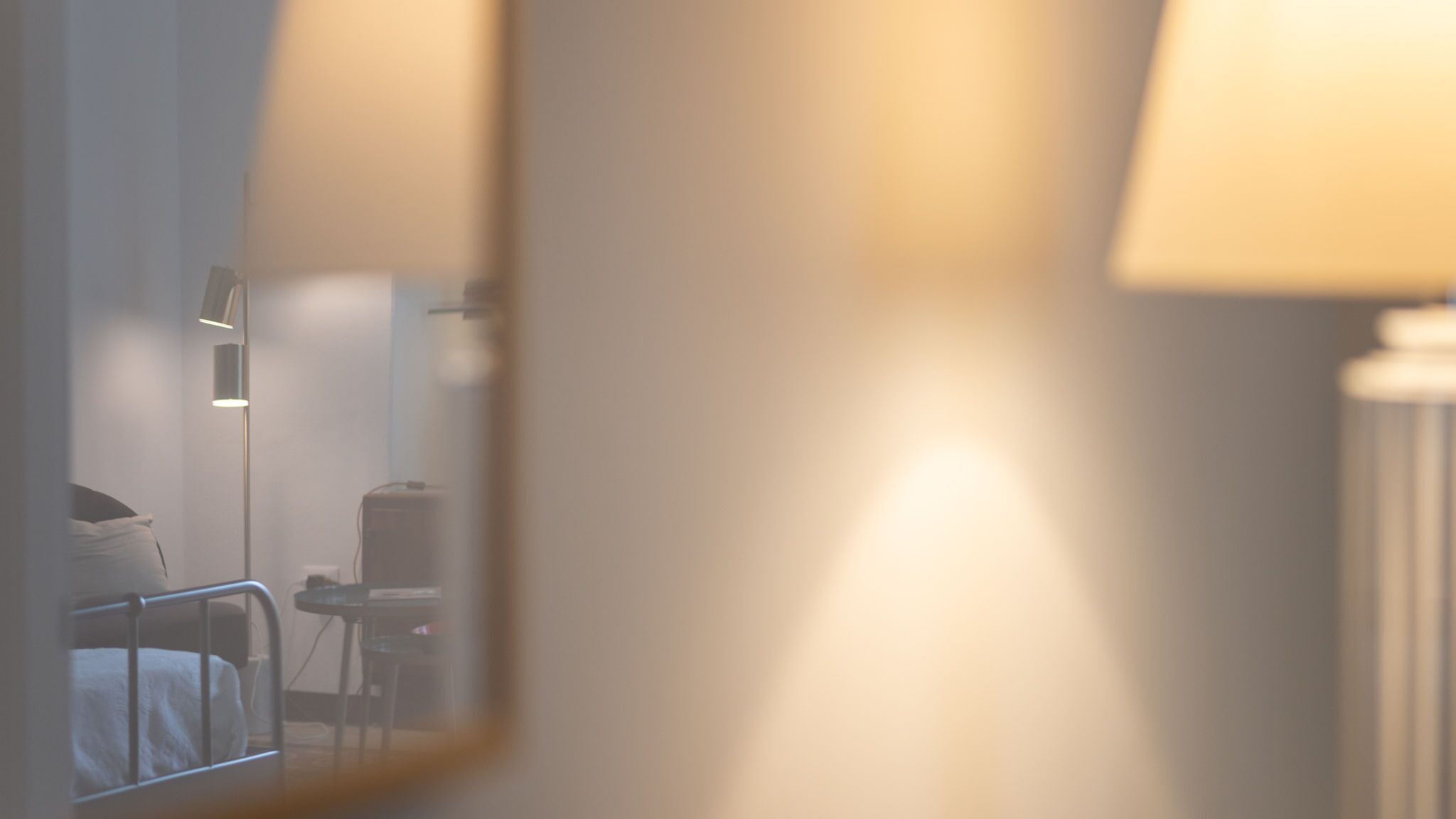 A dimly lit room with a bed, a bedside table, and a lamp.