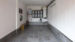 A hallway with grey tiled flooring, a fire extinguisher, a ladder, and a water dispenser.