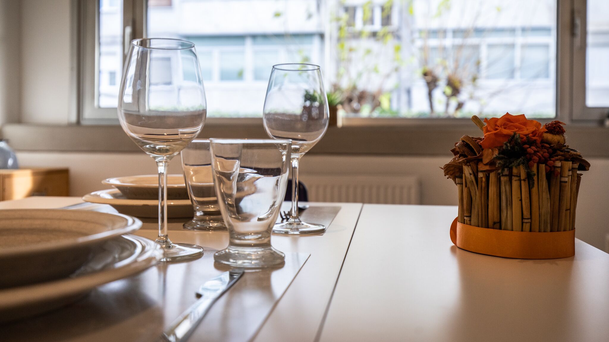 Spisebord med tre vinglas og en vase med visne blomster.