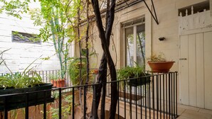 A courtyard with potted plants, a tree, and a white building with a window and door. - Italianway - Casa del Barone (Lecce)