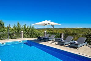 Una piscina al aire libre, sillones reclinables de piscina