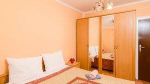 Un dormitorio con cama, mesita de noche, lámpara roja, armario de madera y una puerta.