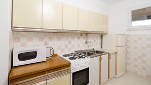 Una cocina con armarios blancos, microondas, estufa y refrigerador.