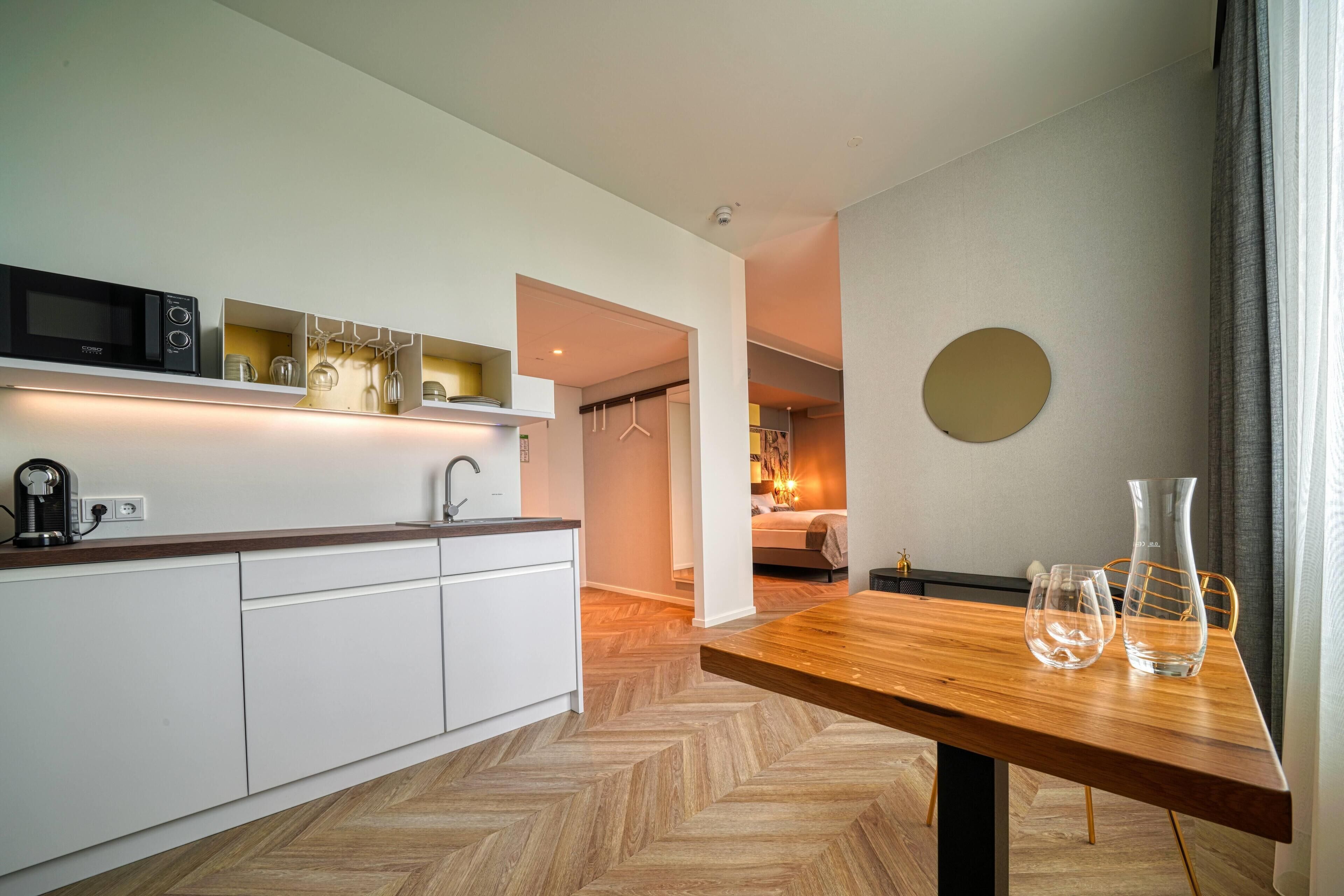 A modern kitchen with white cabinets, a wooden countertop, and a dining area with a wooden table.